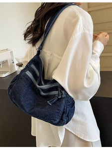 Large denim tote bag with multiple zip pockets shown on model in a cozy cafe