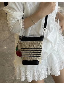 Rainbow striped woven bucket bag with black leather trim and cherry charm on model