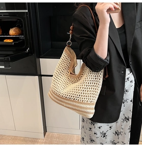 Detail of hollow woven shoulder bag featuring brown leather straps and wooden bead accents