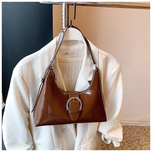 Close-up of brown patent leather hobo bag featuring a large silver horseshoe buckle