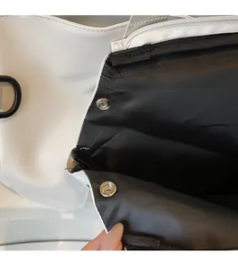 Close-up of black and white tote bag interior with metal snap buttons and zipper