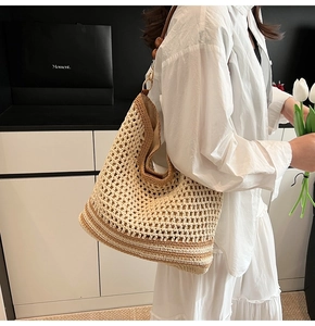 Detail of hand-crocheted straw tote bag featuring wooden beads and metal ring shoulder strap