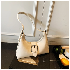 Close-up of cream hobo bag with large silver buckle on a stylish photography book