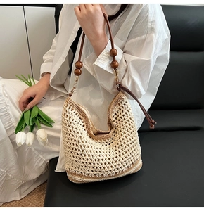 Close-up of woven straw bag with vintage wood beads on leather shoulder strap
