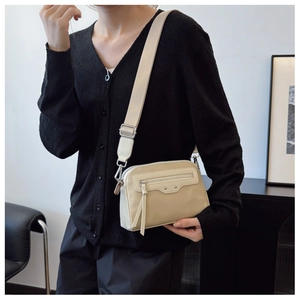Détails du sac bandoulière beige avec double zip, franges et large sangle en tissu