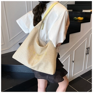 Dettaglio della borsa tote intrecciata con ricamo giallo e tracolla coordinata