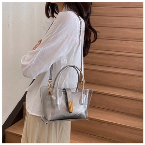 Silver jelly tote bag shown with a long shoulder strap on a model indoors