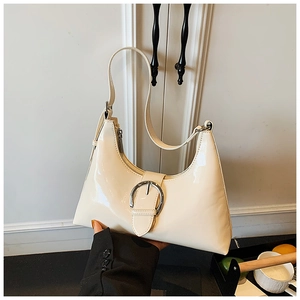 Detail of a creamy white glossy patent leather underarm bag with a large silver buckle