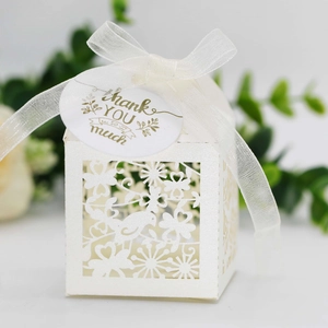 Close-up of white laser-cut favor box with birds, floral patterns and Thank You tag