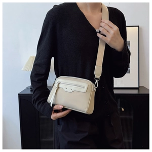 Détail du sac à bandoulière beige minimaliste avec sangle large et ferrures argentées