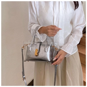 Détail du sac argenté en PVC transparent avec poche intérieure et fermoir rotatif doré
