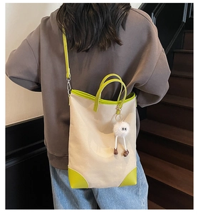 Detail of canvas tote bag with neon green leather trim and cute plush doll pendant charm