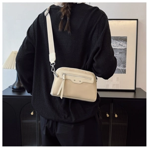 Détail d'un sac bandoulière beige avec fermeture éclair à gland et large sangle tendance