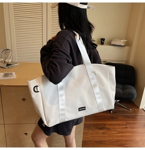 Detail of a large white waterproof nylon tote bag with wide straps and square logo tag