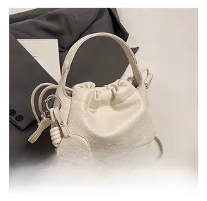 Close-up of white lychee leather bucket bag with drawstring closure and cute dog charm