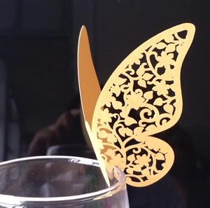Macro shot of gold laser-cut butterfly place card on a wine glass for wedding decor