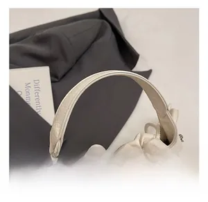 Detail of cream pleated handbag showing lychee texture leather and silver metal buckles