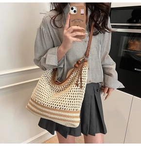 Detail of beige hollow-out woven tote bag with leather strap and wooden bead charm