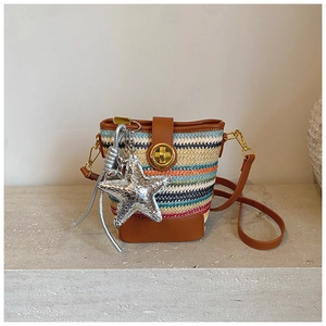 Close-up of multicolored woven bucket bag with leather strap and silver star pendant