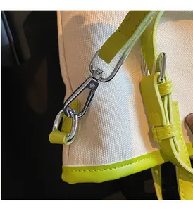 Macro shot of silver metal hook and vibrant green leather trim on white canvas tote bag