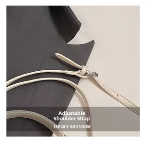 Close-up of adjustable leather shoulder strap with silver buckle on pleated bucket bag