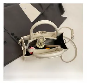 Vue intérieure du sac à main blanc montrant les compartiments et les accessoires de maquillage