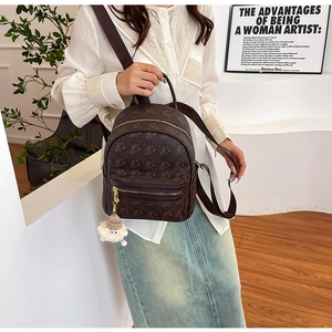 Detail of brown faux leather backpack with cartoon bear embossing and plush charm