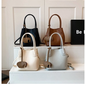 Détail de quatre sacs seaux colorés avec texture cuir litchi et breloques éléphant