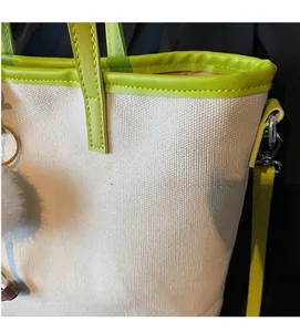 Close-up of canvas texture and green leather trim on a minimalist tote bag detail