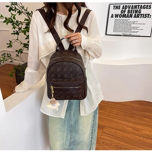 Deep brown mini backpack with bear pattern and plush pendant shown in modern home setting