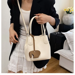 Détail du sac seau en cuir beige avec un charmant pendentif éléphant marron attaché