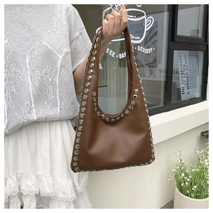 Detail shot of a dark brown shoulder bag with silver metal rivets and PU leather finish