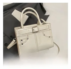 Détail du sac à main beige avec coutures décoratives, rivets et boucle métallique élégante