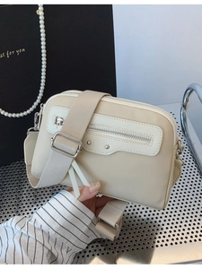 Sac bandoulière beige minimaliste avec large sangle et rivets métalliques de style chic
