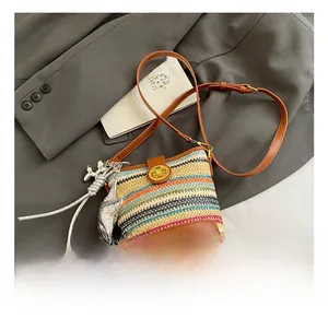 Detail of colorful woven bucket bag with brown leather trim and golden metal turn lock