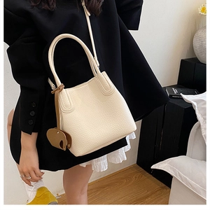 Détail du sac seau en cuir grainé blanc crème avec breloque éléphant et poignée incurvée