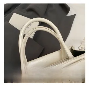 Gros plan du sac à main en cuir blanc crème avec doubles poignées et détails de couture