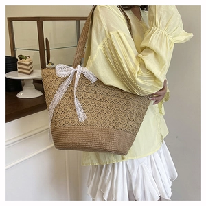 Close-up of a large straw tote bag with white lace bow decoration in a lifestyle setting