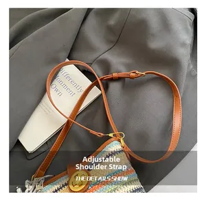 Detail of woven bucket bag with adjustable leather strap and golden metal buckle