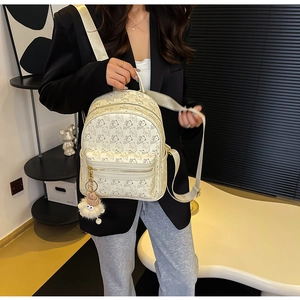 Close-up of cream PU leather backpack with bear prints and plush charm on the model