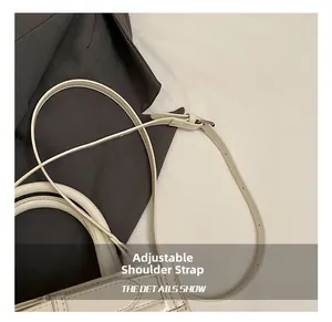 Détail d'un sac à main blanc gaufré crocodile avec bandoulière réglable sur veste