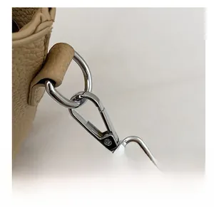 Detail showing the silver metal detachable swivel hook on beige litchi leather bag