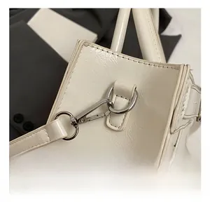 Détail du crochet en métal argenté poli et coutures fines sur le sac en cuir blanc