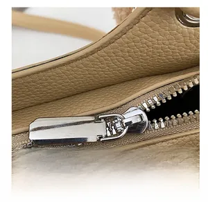 Macro view of high-quality silver metal zipper on lychee textured beige leather handbag