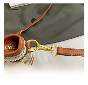 Detailed macro of golden metal lobster clasp and brown leather trim on woven bucket bag
