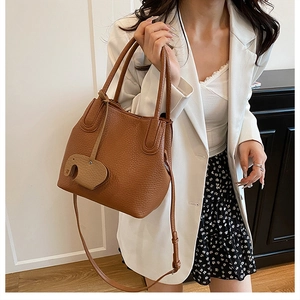 Sac seau marron en cuir texturé avec charme éléphant porté par un mannequin chic