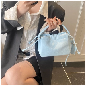Detail view of light blue lychee grain handbag with drawstring and butterfly charm