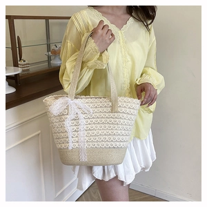 Close-up of woven straw tote bag featuring white lace trim and a large decorative bow