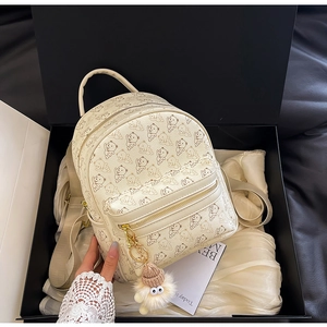 Detail of cream mini backpack with bear print, plush charm and metal zipper on silk lining