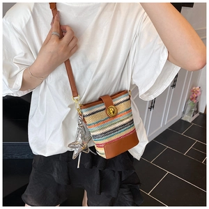 Detail of colorful woven mini bucket bag with leather trim and silver star pendant accessory